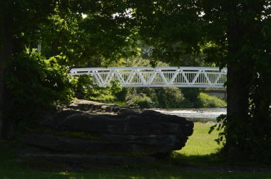 A beautiful walking bridge shown framed thru the trees at Turtle Island, Smiths Falls, Ontario during the springtime.