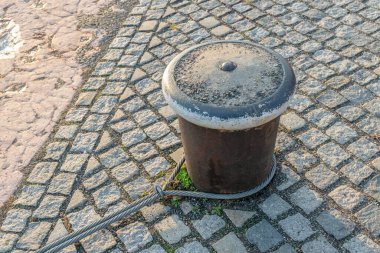 Siyah demir kaldırım taşı, eski ve eski püskü, taştan bir arka planı var.