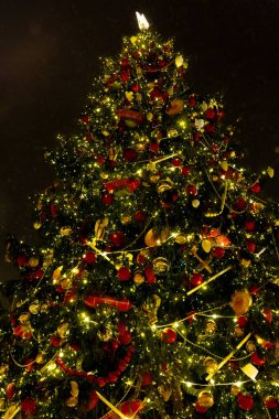 Yanan bir çelenkle süslenmiş Noel ağacı.