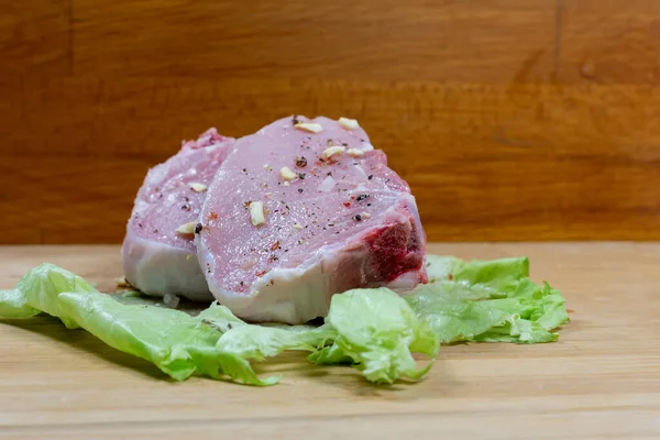 Rohes Schweinefleisch Auf Einem Blatt Salat Auf Einem Hölzernen Hintergrund — Stockfoto