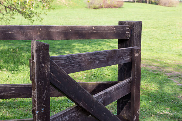 открытые деревянные ворота загона для скота на фоне залитых солнцем лугов