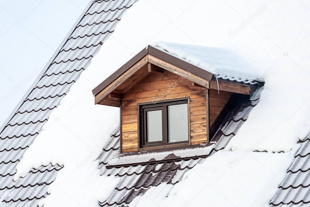 close-up of a mansard plastic window on a country house, the roof is covered with snow