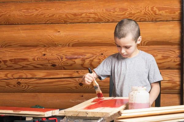 Chłopiec Maluje Drewnianą Podróbkę Pędzlem Czerwono Wiejskim Domu Malowanie Ścian — Zdjęcie stockowe