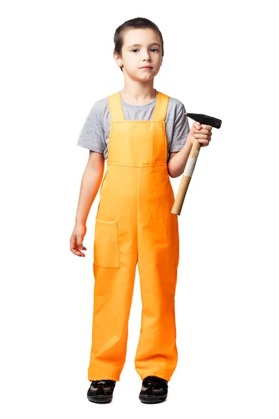 一个面带微笑的男孩木匠穿着橙色工作服摆出姿势 手里拿着一把锤子 在白色孤立的背景下玩乐 度假时穿的儿童服装 — 图库照片