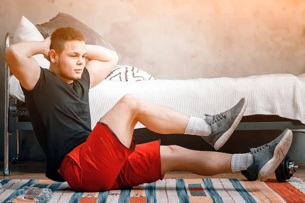 若い男は家でスポーツに行き オンラインで訓練する 選手はプレス 背景のベッド カーペットを作る — ストック写真