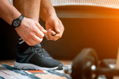 Siyah bağcıkları, halterleri ve arka planda yatağı olan genç bir adam.