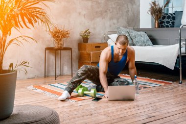 Genç kadın spor için eve gider. Evdeki yerde dinlenen siyah saçlı neşeli sporcu kadın, film izliyor ve yatak odasındaki dizüstü bilgisayardan ders çalışıyor.
