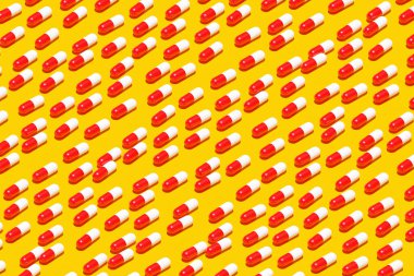 3 boyutlu illüstrasyon beyaz - kırmızı kapsüller, sarı zemin üzerinde sıralanmış ilaçlarla dolu tabletler. Kapsül ilacı