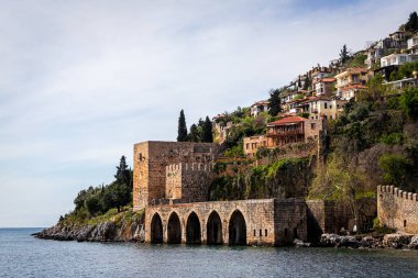 Denize bakan bir tepenin üzerine kurulmuş güzel bir ortaçağ kasabası manzarası. Güneşli bir günde Alanya 'da tersane ve cephanelik, Türkiye