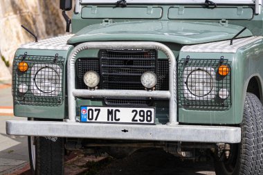 Antalya, Türkiye 12 Nisan 2021: yeşil Land Rover Defender. Farın, tamponun, tekerleğin, logo radyatör ızgarasının, kaputun yakın çekimi..   