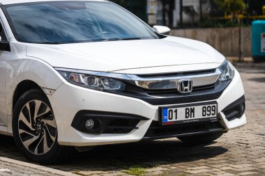 Alanya, Türkiye 12 Nisan 2021: Beyaz Honda Civiç sıcak bir yaz gününde ağaçların, palmiyelerin önüne park etti 
