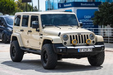 Alanya, Türkiye 12 Nisan 2021: Bej rengi Jeep Wrangler sıcak bir yaz gününde park alanının önüne park etti 