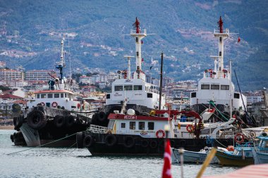 Alanya, Türkiye 12 Nisan 2021: Limandaki gemiler, deniz kıyısındaki rıhtım, dağdaki kentin arka planına karşı. Deniz taşımacılığı. Yolculuk. 