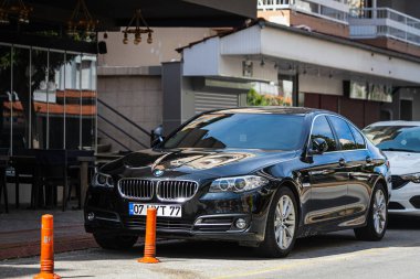 Alanya, Türkiye 12 Nisan 2021: Siyah BMW 5 serisi sıcak bir yaz gününde caddeye park edildi. 