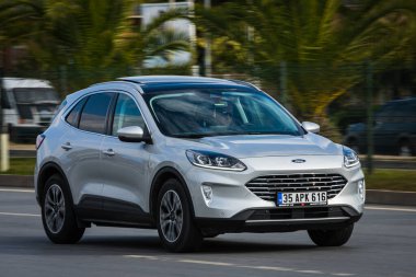 Alanya, Türkiye 13 Nisan 2021: Gümüş rengi Ford Puma sıcak bir yaz gününde palmiyelerin arka planına doğru hızla sürüyor  