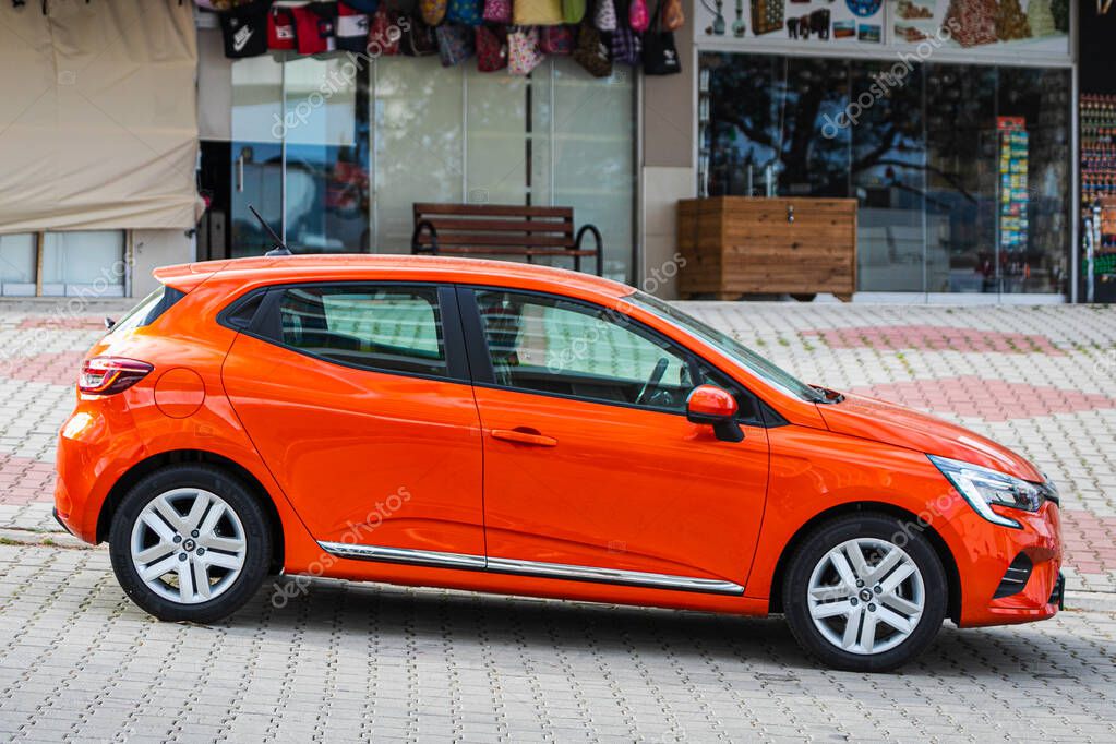 Alanya, Turkey  April 13 2021:  orange Renault Clio  is parked  on the street on a warm summer day against the backdrop of a buildung, shops