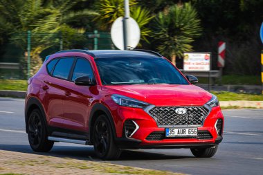 Alanya, Türkiye 13 Nisan 2021: Kızıl Hyundai Tucson sıcak bir yaz gününde palmiyelerin arkasına doğru hızla sürüyor  