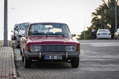 Alanya, Türkiye 13 Nisan 2021: Sıcak bir yaz gününde kırmızı Ford 20M, bir sokak, palmiyeler, ön taraf karşı caddeye park edilmiştir.  