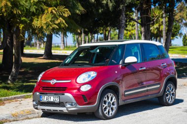 Alanya, Türkiye 15 Nisan 2021: Sıcak bir yaz gününde park yerine park etmiş kırmızı Fiat 500. Ağaçlar, palmiyeler 