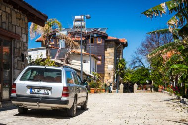 ; Türkiye 15 Nisan 2021: Mercedes E-Sınıfı 250d sıcak bir yaz gününde eski sokak, ağaçlar, palmiyeler 