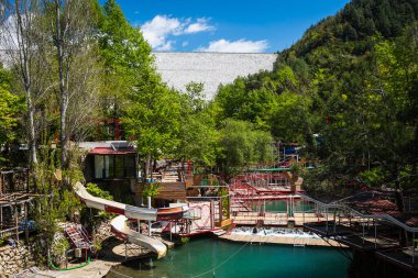 Bir kafesi ve dağ nehri üzerinde bir su parkı olan boş bir turistik alan ve arka planda bir bahçe.