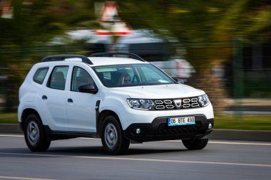 Alanya, Türkiye 17 Nisan 2021: Beyaz Renault DUSTER sıcak bir yaz gününde palmiyelerin arkasına doğru hızla sürüyor  