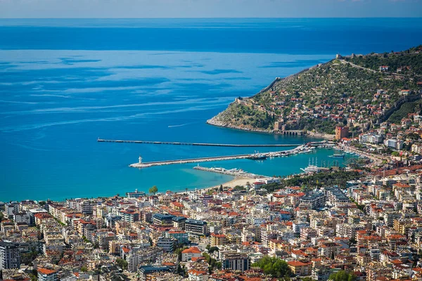 Güzel beyaz bir deniz feneri ve mavi denizin arka planında bir sürü tekne ve yat olan bir rıhtım manzarası.