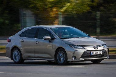 Alanya, Türkiye 16 Nisan 2021: Gümüş rengi Toyota Corolla sıcak bir yaz gününde bir palmiye ağacının zeminine doğru hızla sürüyor 