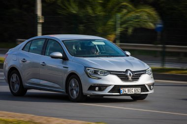 Alanya, Türkiye 17 Nisan 2021: Gümüş Renault Megane sıcak bir yaz gününde palmiyelerin arkasına doğru hızla sürüyor  