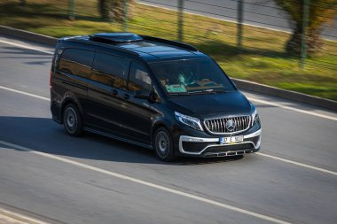 Alanya, Türkiye 13 Nisan 2021: Siyah Mercedes-Benz Vito sıcak bir yaz gününde bir palmiye ağacının arka planına doğru hızla sürüyor  