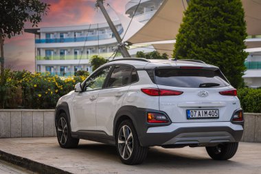 Alanya, Türkiye 17 Nisan 2021: Ilık bir yaz gününde beyaz Hyundai Kona bir binanın, ağaçların, gün batımının zeminine park etti 