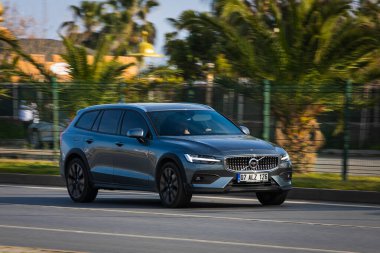 Alanya, Türkiye 17 Nisan 2021: Siyah Volvo V60 Kros Ülkesi sıcak bir yaz gününde bir palmiye ağacının zeminine doğru hızla sürüyor  