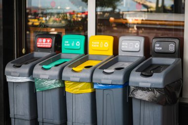 Sokakta beş çöp kutusu var: maskeler için kırmızı, cam için yeşil, plastik ve ambalaj için sarı, metal için gri ve artık atık için siyah. Çöp ayıklama kavramı.