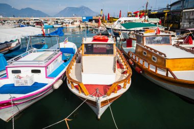 Tahta tahtalar, beyaz ve kahverengiye boyanmış, deniz suyunun arka planına bağlı halatlarla iskeleye demirlenmiş..