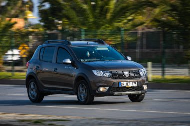 Alanya, Türkiye 13 Nisan 2021: Kahverengi Renault DUSTER sıcak bir yaz gününde bir palmiye ağacının zeminine doğru hızla sürüyor  