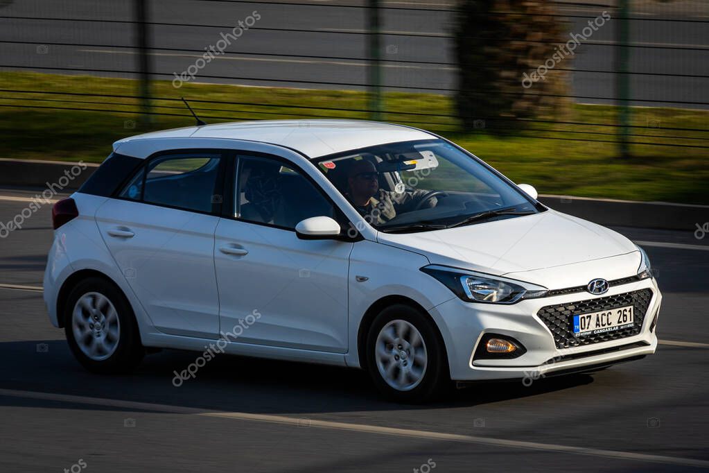 Alanya, Turkey   April 17  2021:    white Hyundai i20    is driving fast on the street on a warm summer day against the backdrop of a  palms