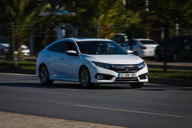 Alanya, Türkiye 13 Nisan 2021: Siyah Honda Civiç sıcak bir yaz gününde palmiyelerin arkasına doğru hızla sürüyor  