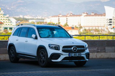 Alanya, Türkiye 19 Nisan 2021: Sıcak bir yaz gününde beyaz Mercedes GLB park yeri ve şehrin arka planına park etti 