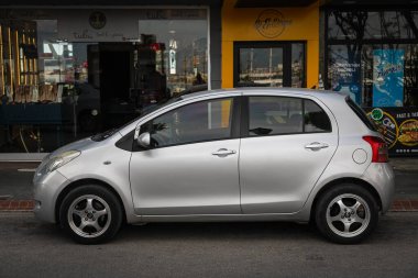 Alanya, Türkiye 17 Nisan 2021: Gümüş renkli Toyota Yaris, sıcak bir yaz gününde bir binanın, caddenin, dükkanların zeminine park etti 