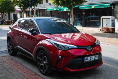 Alanya, Türkiye 17 Nisan 2021: Kızıl Toyota C-HR sıcak bir yaz gününde bir binanın, ağaçların, dükkanların zeminine park etti 