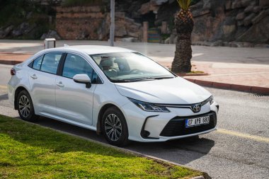 Alanya, Türkiye 17 Nisan 2021: Beyaz Toyota Corolla, sıcak bir yaz gününde bir binanın, caddenin, dükkanların zeminine park etti. 