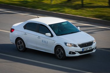 Alanya, Türkiye 17 Nisan 2021: Beyaz Peugeot 301 sıcak bir yaz gününde bir palmiye ağacının arka planına doğru hızla sürüyor  