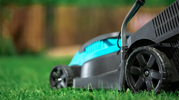 Lawn grass mowing. Worker cutting grass in a green yard. A man with an electric lawn mower mowing a lawn. Gardener pruning a garden