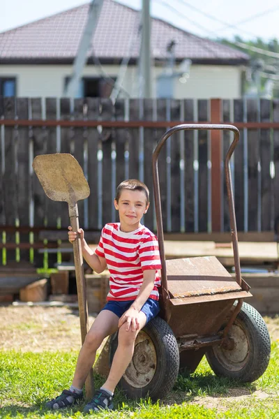 Little Cheerful Boy Sits Garden Wheelbarrow Holds Shovel His Hand — Stock Photo, Image