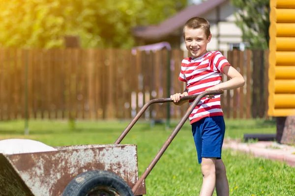 Little Boy Drives Wheelbarrow Bags Sunny Day Garden Boy Assistant — Stock Photo, Image