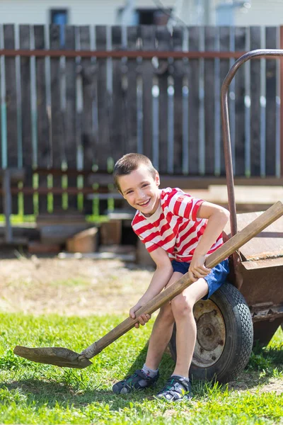 Little Cheerful Boy Sits Garden Wheelbarrow Holds Shovel His Hand — Stock Photo, Image