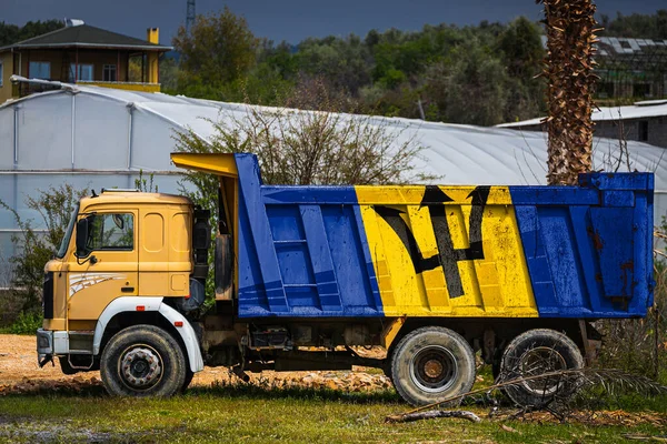 Dump truck with the image of the national flag of Barbados is parked against the background of the countryside. The concept of export-import, transportation, national delivery of goods