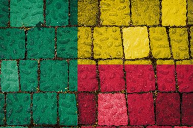 Taştan duvar arkasında Benin 'in ulusal bayrağı. Taş dokusu arka planında bayrak pankartı.