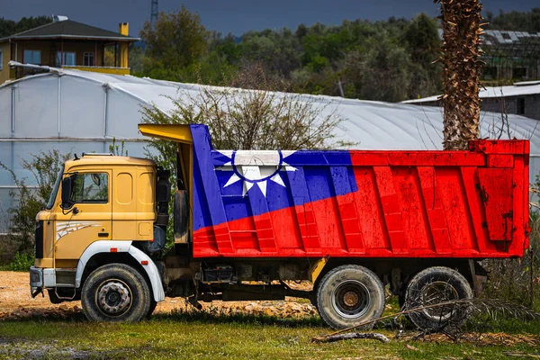 Dump truck with the image of the national flag of Taiwan is parked against the background of the countryside. The concept of export-import, transportation, national delivery of goods