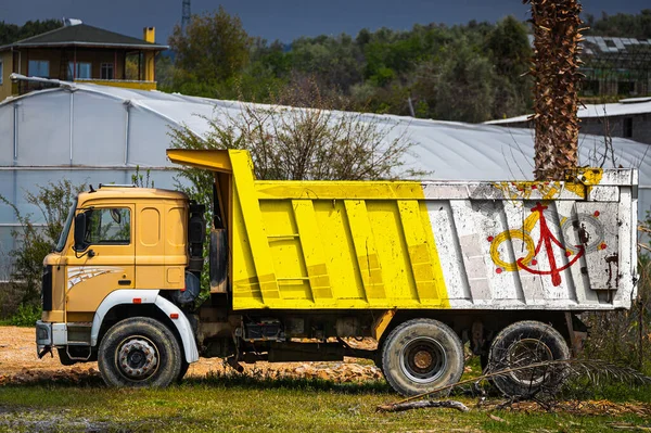 Dump truck with the image of the national flag of Vatican is parked against the background of the countryside. The concept of export-import, transportation, national delivery of goods